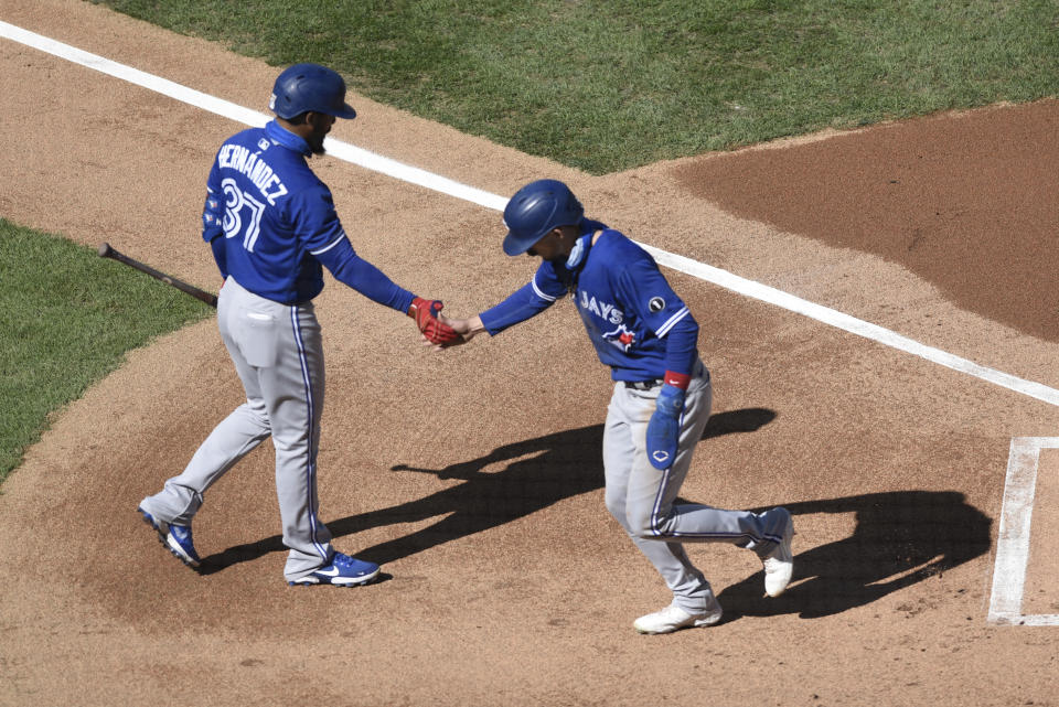 Toronto Blue Jays' Cavan Biggio, right, scores on a balk and is greeted by Teoscar Hernandez during the first inning of a baseball game against the Philadelphia Phillies, Sunday, Sept. 20, 2020, in Philadelphia. (AP Photo/Michael Perez)