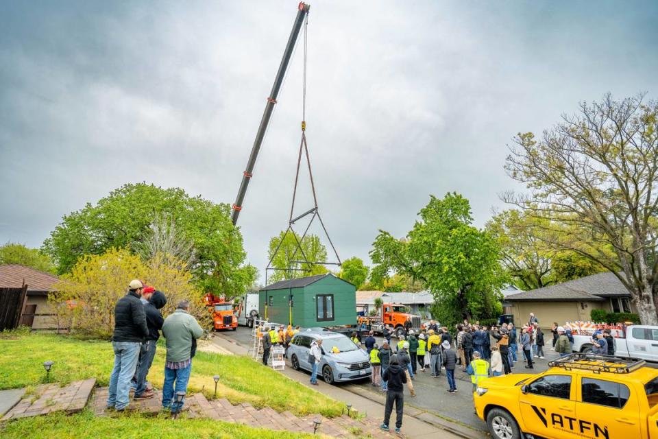 A crowd gathers to watch an ADU get lifted into the backyard of a South Land Park residence on Thursday.