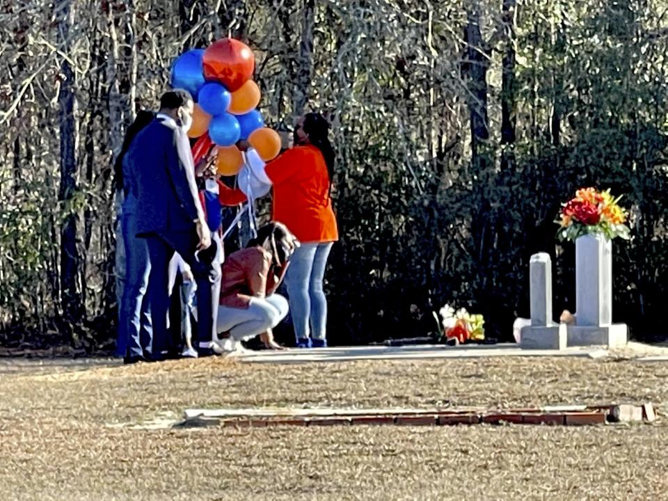 FILE - In this Feb. 23, 2021, file photo, Wanda Cooper-Jones kneels before the grave of her son, Ahmaud Arbery, at the New Springfield Baptist Church in Waynesboro, Ga., to mark the one year anniversary of Ahmaud Arbery's death in Brunswick, Ga. The Justice Department announced federal hate crime charges Wednesday, April 28, 2021, in the death of Arbery, who was killed while out for a run.(AP Photo/Lewis M. Levine, file)