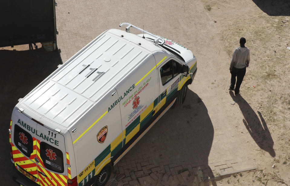 In this photo taken Tuesday, May 19, 2020, an ambulance passes a pedestrian in Khayelitsha in Cape Town South Africa. With dramatically increased community transmission, Cape Town has become the center of the COVID-19 outbreak in South Africa and the entire continent. (AP Photo/Nardus Engelbrecht)