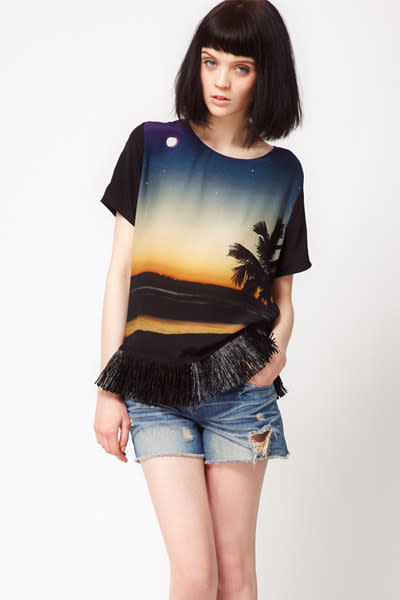 Fehlt zum vollendeten Sommer-Look ja eigentlich nur noch eines: die echte Sonne. Wie schön, dass sie auf diesem Shirt mit Bast-Saum gerade aufgeht. Die warme Jahreszeit, die kann jetzt wirklich kommen. (Bild: asos.de / Lulu & Co.)