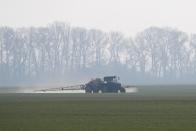 FILE PHOTO: An agricultural worker drives a tractor spreading fertilizers to a field of winter wheat in Kiev region