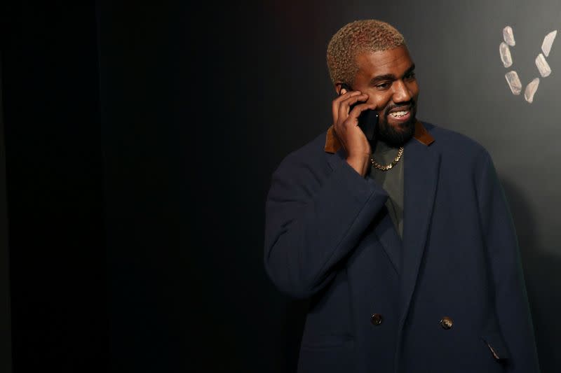 FILE PHOTO: Rapper Kanye West talks on the phone before attending the Versace presentation in New York