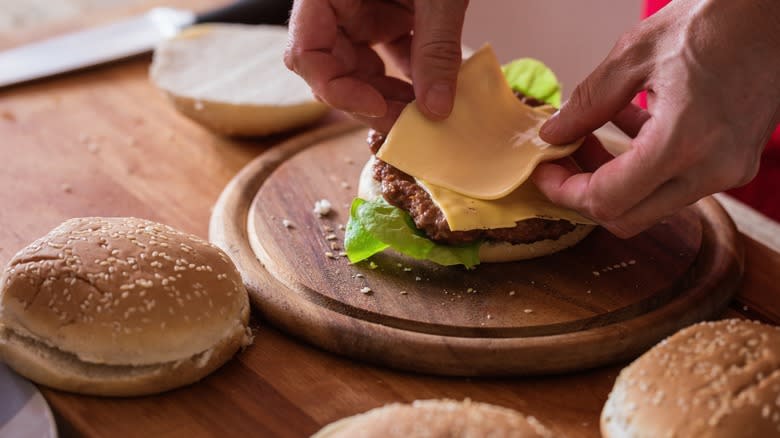 Person's hands preparing a burger