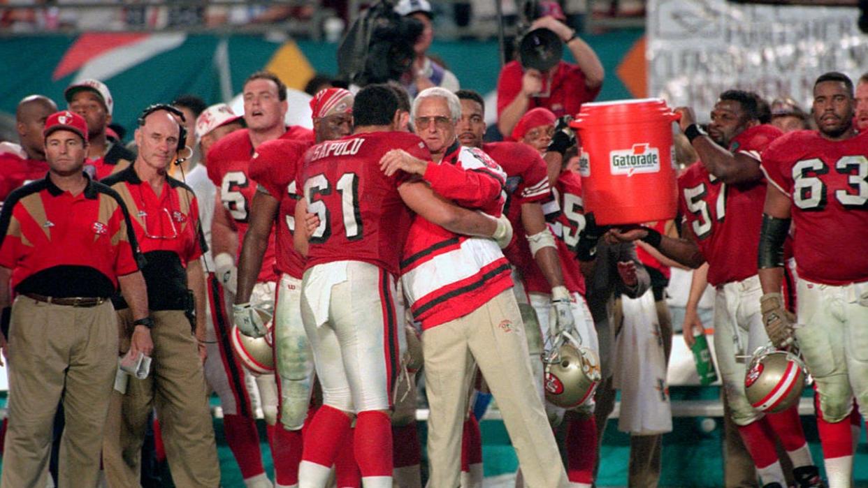 <div>Head coach George Seifert and Jesse Sapolu #61 of the San Francisco 49ers hug as they defeat the San Diego Chargers in Super Bowl XXIX on January 29, 1995 at Joe Robbie Stadium in Miami, Florida. The Niners won the Super Bowl 49-26. (Photo by Focus on Sport/Getty Images)</div>