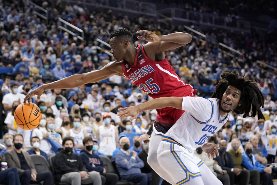 Arizona center Christian Koloko, left, reaches for a loose ball along with UCLA guard Tyger Campbell during the first half of an NCAA college basketball game Tuesday, Jan. 25, 2022, in Los Angeles. (AP Photo/Mark J. Terrill)
