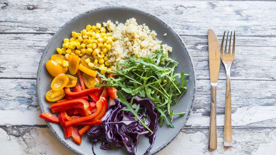 plate of rainbow salad with bulgur, rocket and different vegetables