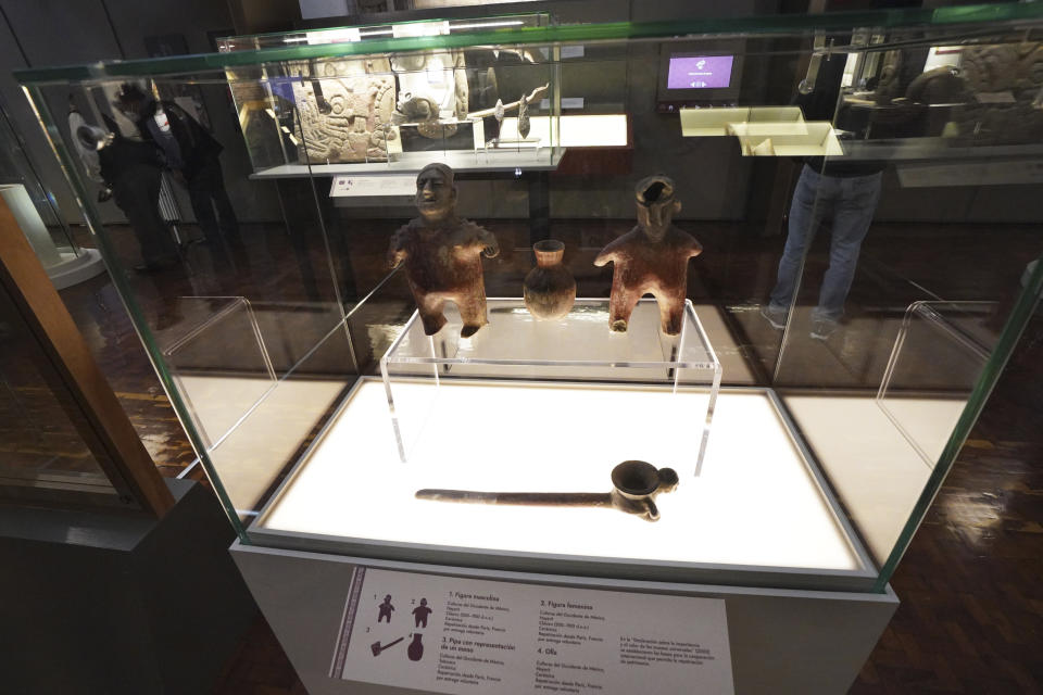 Figurines, a pipe and a small pot are shown as part of the exhibition "The Greatness of Mexico" displaying for the first time in the country more than 800 pieces repatriated from abroad in the last three years and others that were in safekeeping and confiscation warehouses, at the Anthropology Museum in Mexico City, Friday, Oct. 1, 2021. (AP Photo/Marco Ugarte)