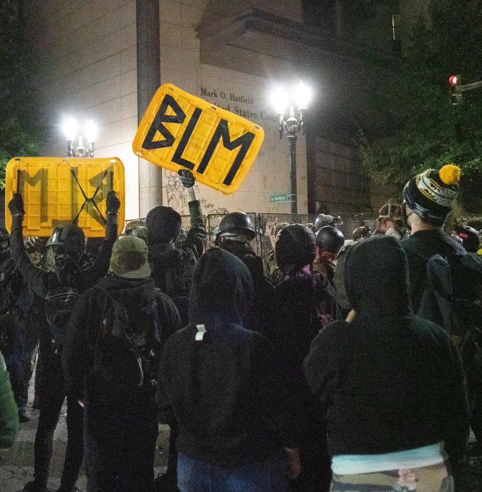 Protesters raise signs outside the federal courthouse in Portland, Ore., in the early morning of July 26, 2020.