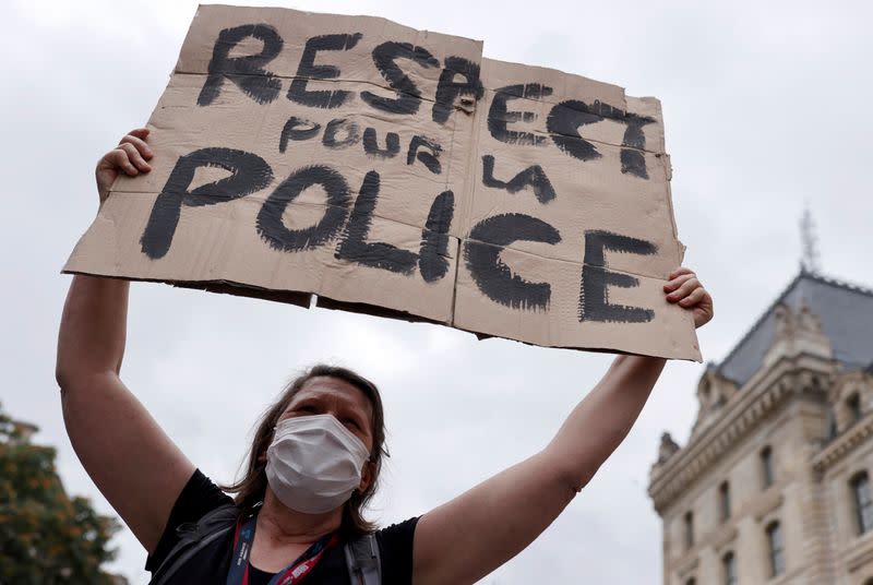 A supporter of police forces wearing a protective face mask holds a banner as she demonstrates in front of the French police headquarters in Paris