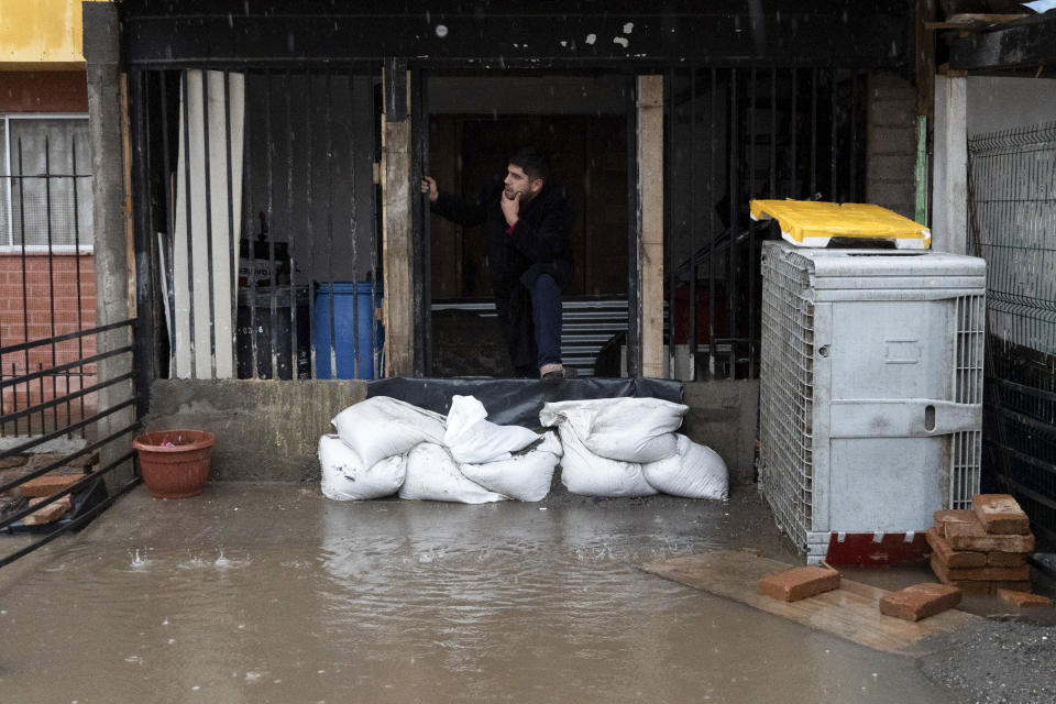 A resident looks out of his front door as floods inundate his neighborhood after heavy rain in Santiago, Chile, Thursday, June 13, 2024. (AP Photo/Matias Basualdo)