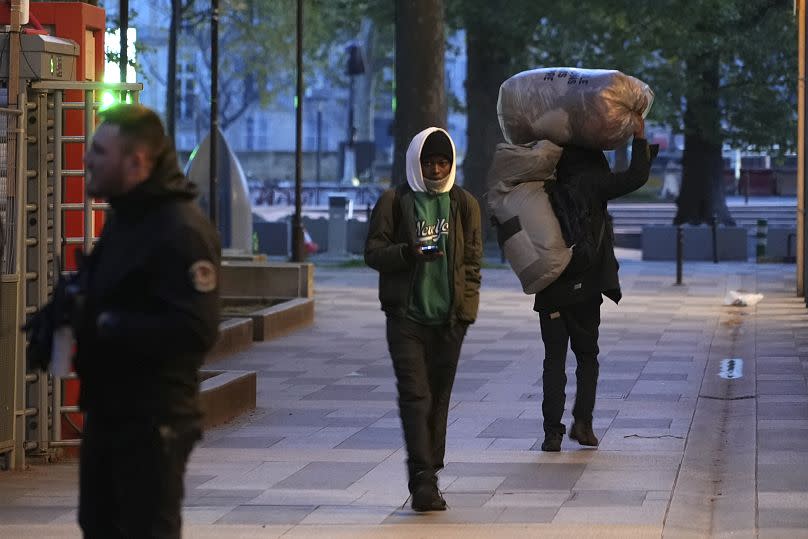 Migrants leave a makeshift camp after being evicted by police officers, early Tuesday April 23, 2024 in Paris.