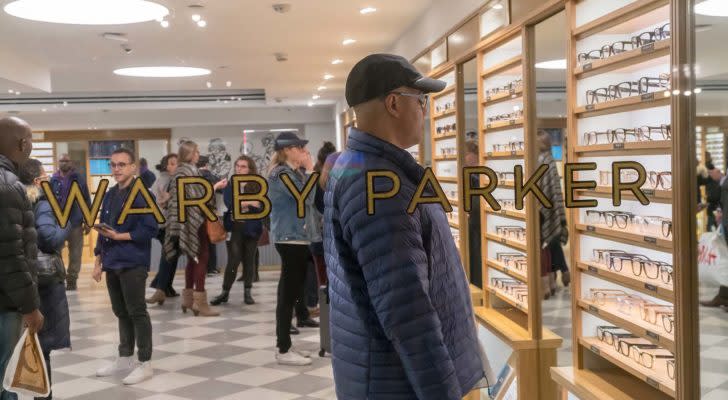 A photograph looking through a glass window as a customer shops for Warby Parker (WRBY) glasses.