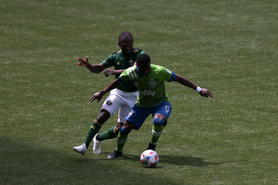 Portland Timbers midfielder Diego Chara, left, fights for possession with Seattle Sounders defender Nouhou (5) during an MLS soccer match in Portland, Ore., Sunday, May 9, 2021. (Sean Meagher/The Oregonian via AP)