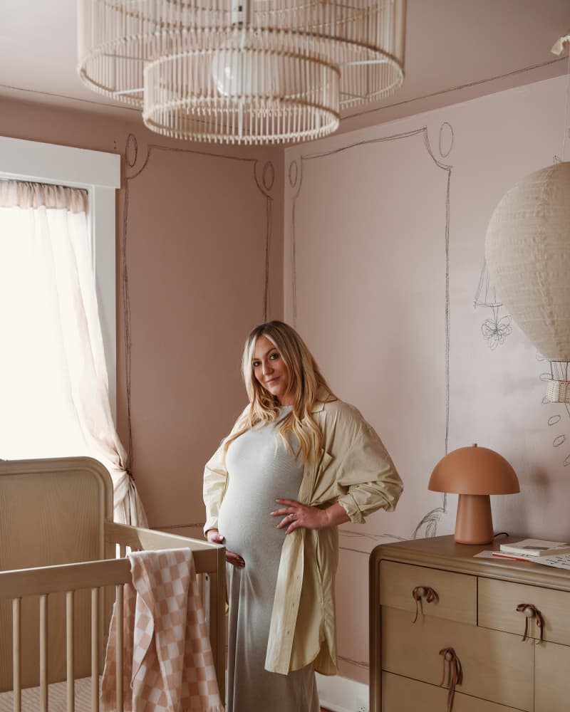 Expectant parent standing in front of crib in newly designed nursery.