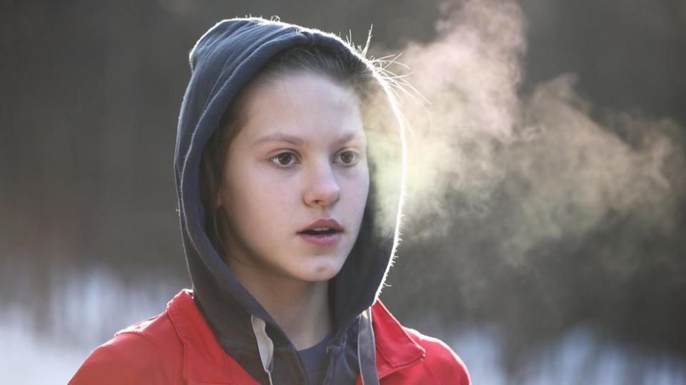 Una joven respira y se observa su aliento por el frío.