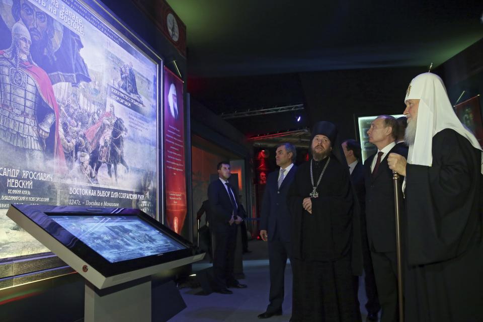 FILE - Russian President Vladimir Putin, second right, Russian Orthodox Patriarch Kirill, right, First Deputy Chief of Staff of the Presidential Administration Vyacheslav Volodin, fourth right, and Archimandrite Tikhon Shevkunov, third right, visit the exhibition "Orthodox Russia, My History, The Rurik Dynasty" at Manezh Exhibition Hall during celebration of the National Unity Day in Moscow, Russia, Tuesday, Nov. 4, 2014. In Russia, history has long become a propaganda tool used to advance the Kremlin's political goals. In an effort to rally people around the flag, the authorities have sought to magnify the country's past victories while glossing over the more sordid chapters of its history. (Mikhail Metzel, Sputnik, Kremlin Pool Photo via AP, File)