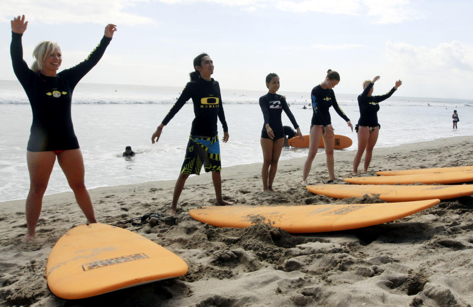 This Aug. 25, 2012 photo shows tourists taking a surfing lesson on Kuta beach, Bali, Indonesia. It can be hard to find Bali's serenity and beauty amid the villas with infinity pools and ads for Italian restaurants. But the rapidly developing island's simple pleasures still exist, in deserted beaches, simple meals of fried rice and coconut juice, and scenes of rural life. (AP Photo/Firdia Lisnawati)