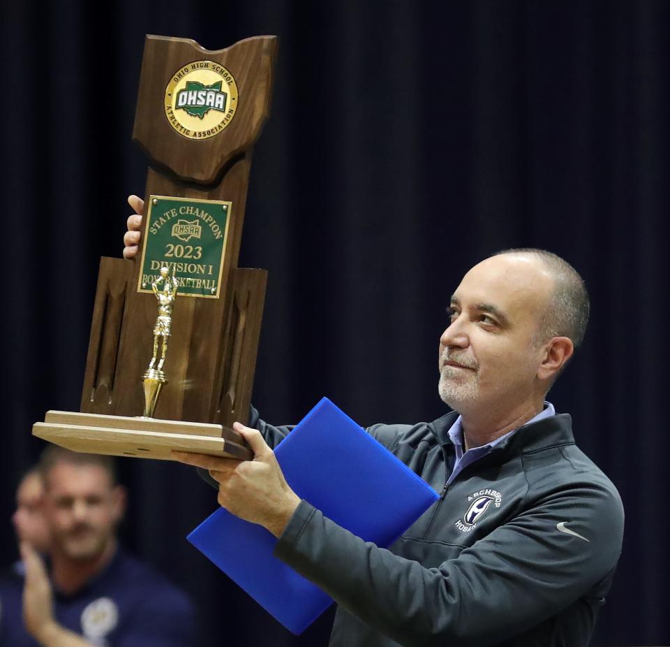 Hoban boys basketball coach TK Griffith holds up the 2023 state championship trophy during a pep rally Barry Gym.