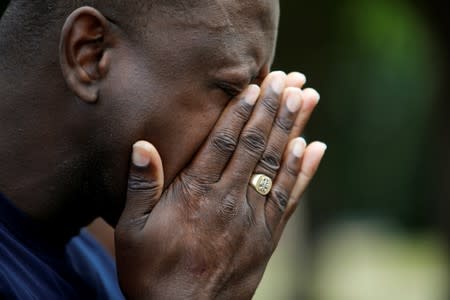 A local resident wipes away tears while praying with other members of his church near a municipal government building where a shooting incident occurred in Virginia Beach, Virginia