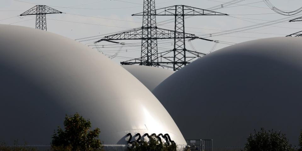 High-voltage pylons sit at a substation behind storage facilities at a biogas plant in Germany.