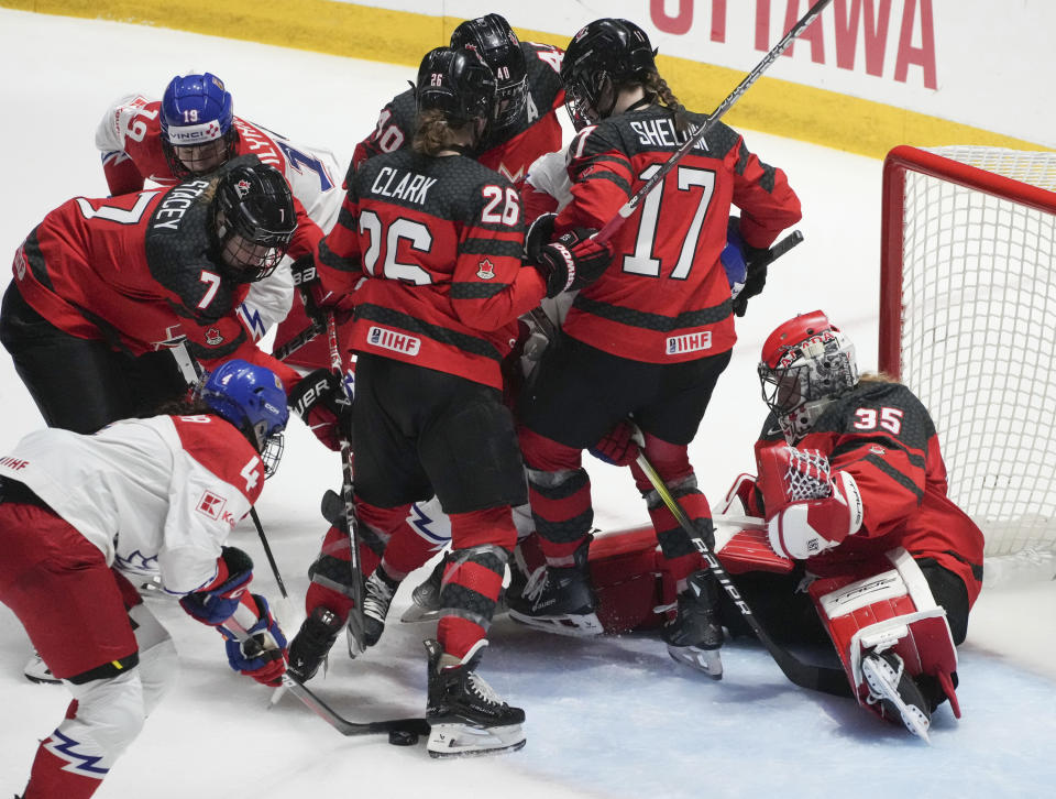 Czechia's Daniela Pejsova (4) digs for a rebound shot as Canada goaltender Ann-Renee Desbiens (35) drops in her net during the third period of a hockey match at the IIHF Women's World Championships in Utica, N.Y., Sunday, April 7, 2024. (Christinne Muschi/The Canadian Press via AP)