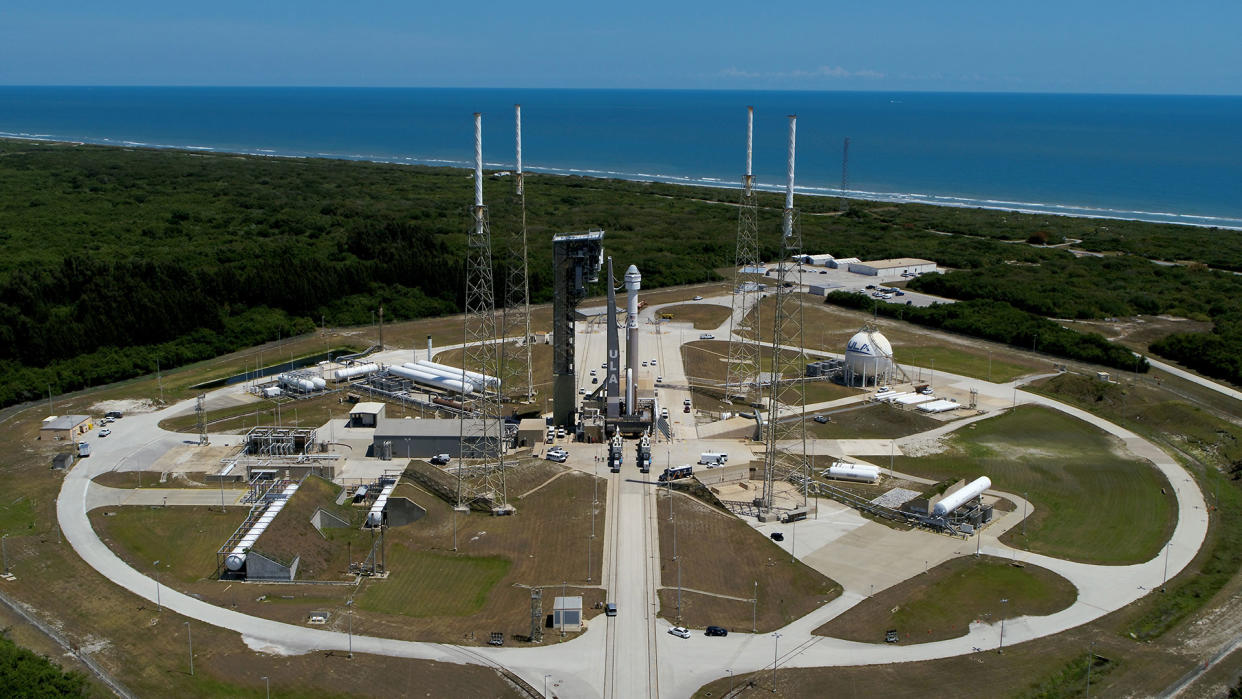  Long-distance view of a rocket standing on a launch pad with the ocean in the background. 