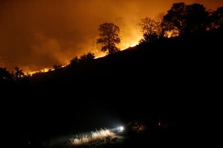 A firefighting truck is seen parked along a firebreak beneath a burning ridge during the Detwiler fire in Mariposa, California. REUTERS/Stephen Lam