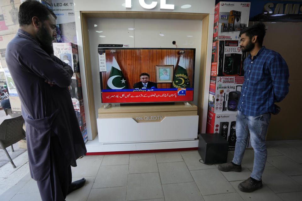 People watch a TV news report about the death of former Pakistani President Gen. Pervez Musharraf at a TV shop in Karachi, Pakistan, Sunday, Feb. 5, 2023. Musharraf, who seized power in a bloodless coup and later led a reluctant Pakistan into aiding the U.S. war in Afghanistan against the Taliban, has died, officials said Sunday. He was 79. (AP Photo/Fareed Khan)