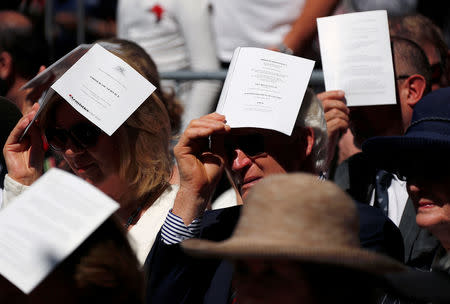 Veterans and their relatives cover their heads from the sun using official programs during a memorial service at the ANZAC Memorial to mark the centenary of the Armistice ending World War One, in Sydney, Australia, November 11, 2018. REUTERS/David Gray