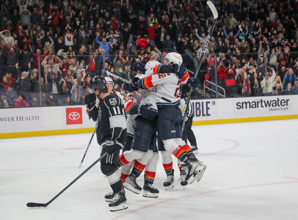 Andrew Poturalski, right, and his teammates celebrate his late score for the Coachella Valley Firebirds to beat the Ontario Reign at Acrisure Arena in Palm Desert, Calif., Dec. 28, 2022. 