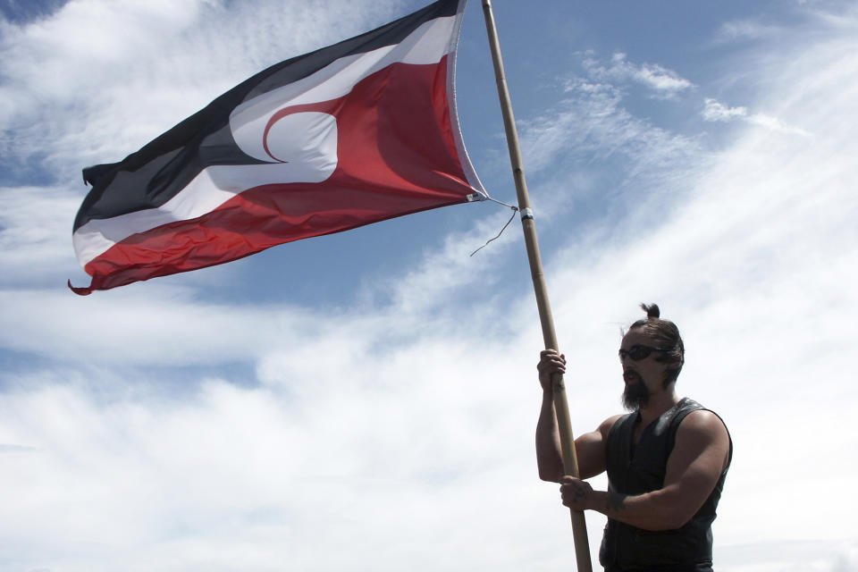 A Maori protester flies the Maori flag known as Tino Rangatiratanga on top of One Tree Hill in Auckland, New Zealand, Feb. 6, 2007. FIFA President Gianni Infantino confirmed the decision on Friday, July 7, 2023, that First Nations flags will be flown at Women's World Cup stadiums in Australia and New Zealand after soccer's world governing body agreed to make exceptions to the usually tight FIFA match day regulations for tournament venues. (Xavier La Canna/AAP Image via AP)