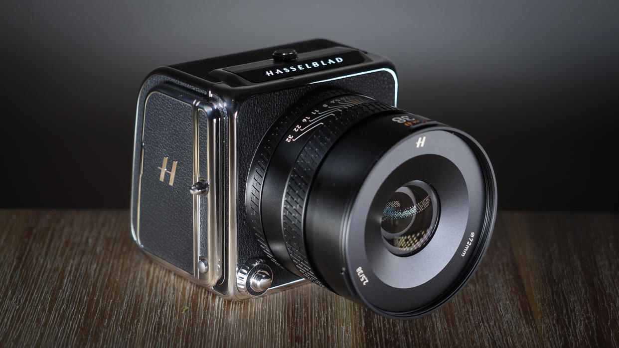  The Hasselblad 907X & CFV 100C medium format camera with digital back, on a wooden table with artistic lighting. 