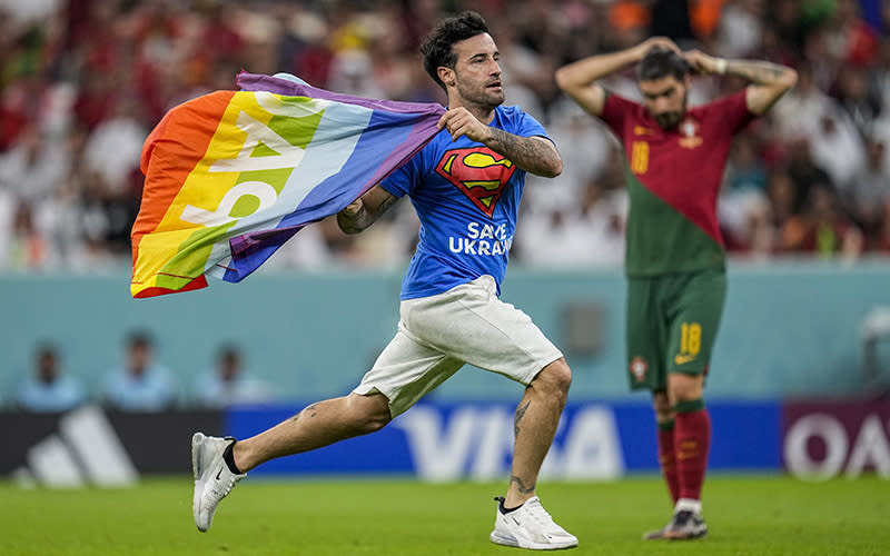 A pitch invader runs across the field with a rainbow flag during the World Cup