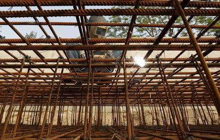 A worker welds iron rods to build a seawall along a river at the construction site of residential and commercial buildings in Ahmedabad June 30, 2015. REUTERS/Amit Dave/Files