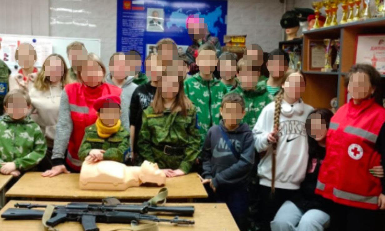<span>A screenshot of a deleted image showing Russian Red Cross staff posing with Kalashnikov rifles at a military event for children.</span><span>Photograph: Battle Brotherhood</span>