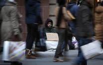 A man who says he is homeless sits on 5th Ave. as shoppers pass, looking for Black Friday sales, in New York November 29, 2013. Black Friday, the day following Thanksgiving Day holiday, has traditionally been the busiest shopping day in the United States. REUTERS/Carlo Allegri (UNITED STATES - Tags: BUSINESS)