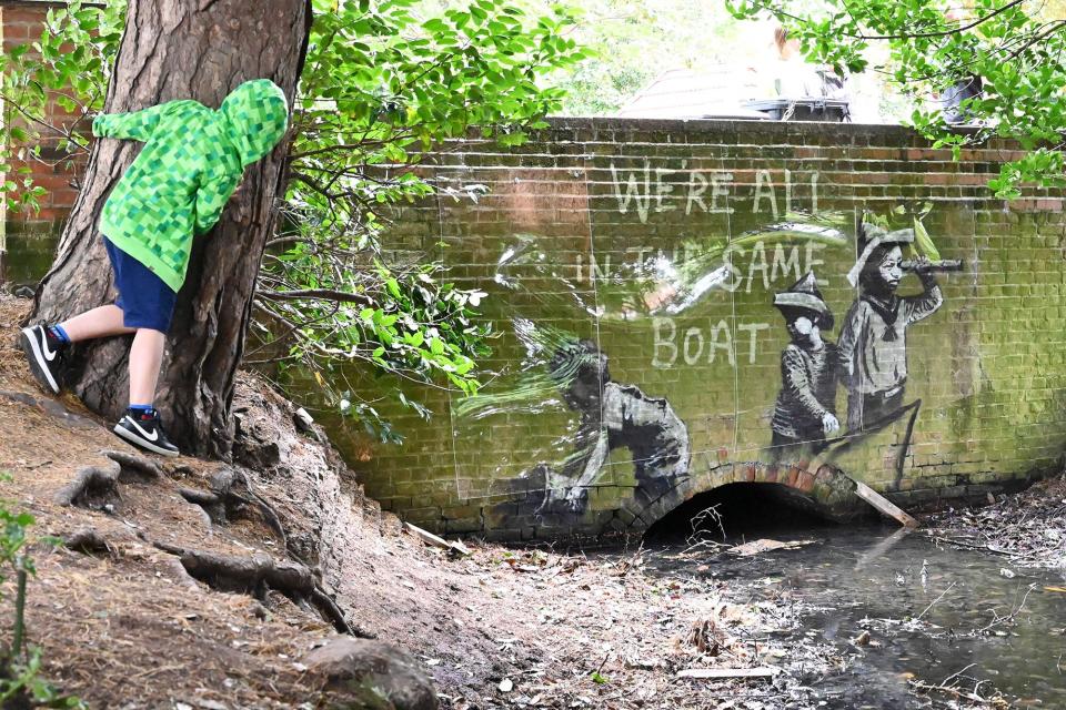 A stensil of children playing at being sailors is the subject of a graffiti artwork bearing the hallmarks of street artist Banksy on the wall of a bridge in Everitt Park in Lowestoft on the East coast of England on August 8, 2021.