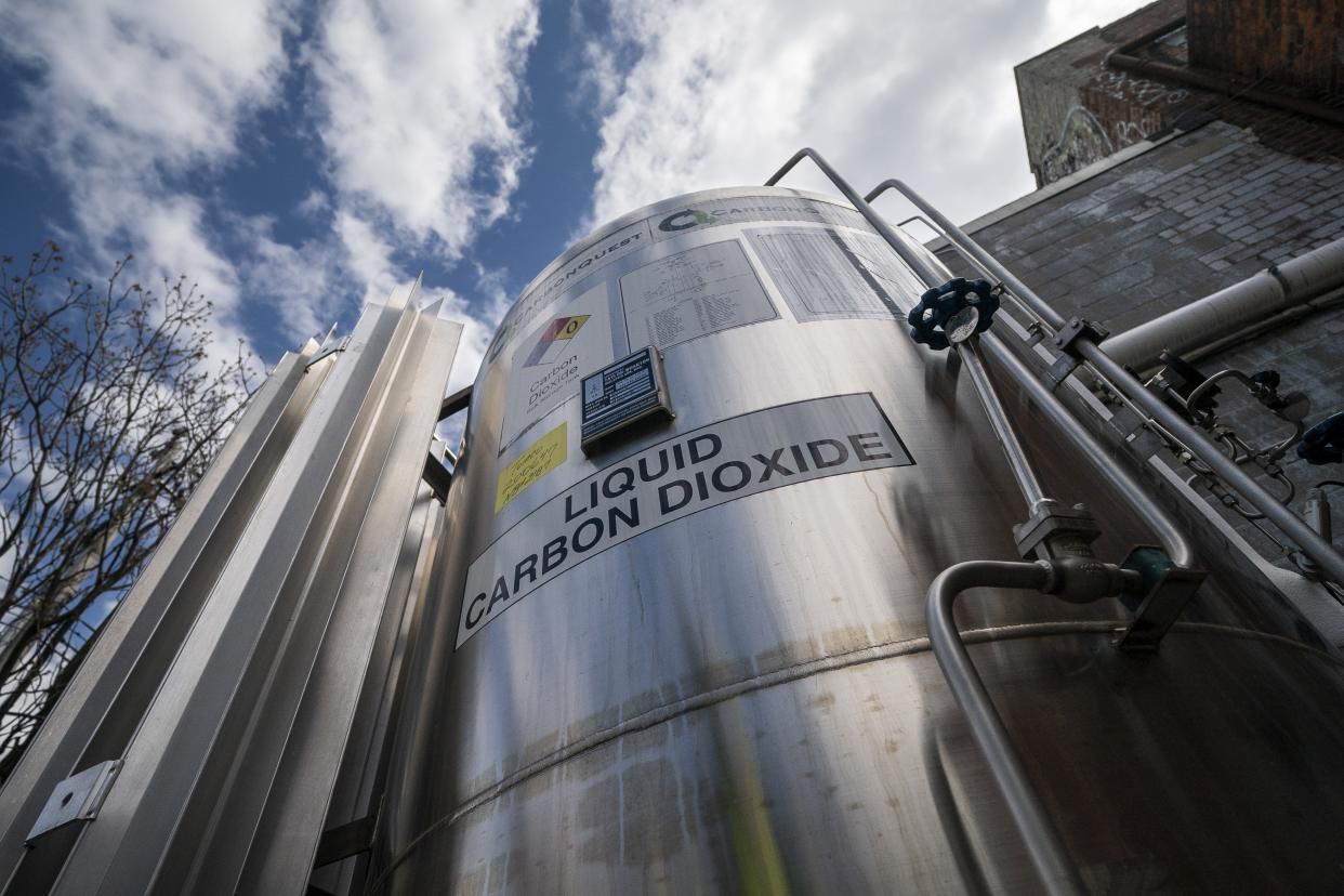 A liquid carbon dioxide containment unit stands outside the fabrication building of Glenwood Mason Supply Company, Tuesday, April 18, 2023, in the Brooklyn borough of New York. New York is forcing buildings to clean up, and several are experimenting with capturing carbon dioxide, cooling it into a liquid and mixing it into concrete where it turns into a mineral. (AP Photo/John Minchillo)