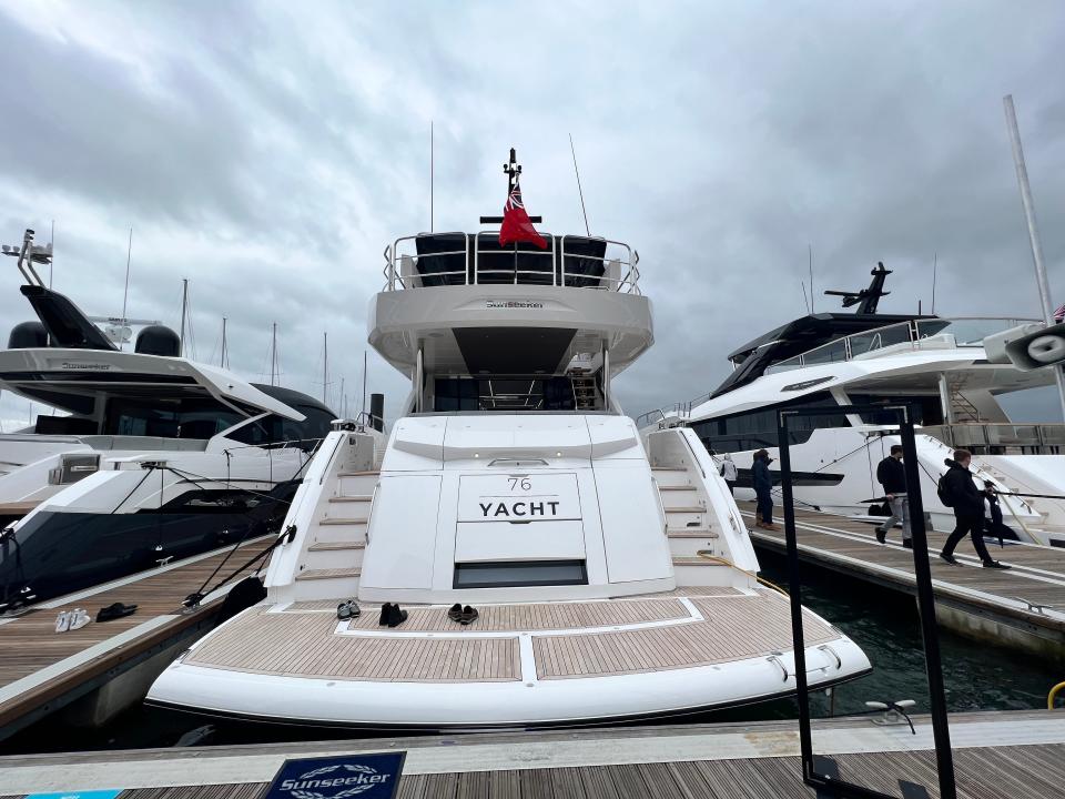 The stern of a Sunseeker 76 yacht flying the British ensign on a cloudy day