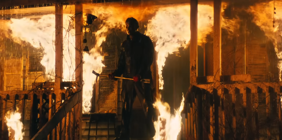 Michael Myers standing outside a house on fire