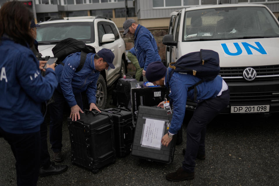 An International Atomic Energy Agency (IAEA) team members unload suitcases with equipment as they arrive to Chernobyl nuclear power plant, in Chernobyl, Ukraine, Tuesday, April 26, 2022. (AP Photo/Francisco Seco)