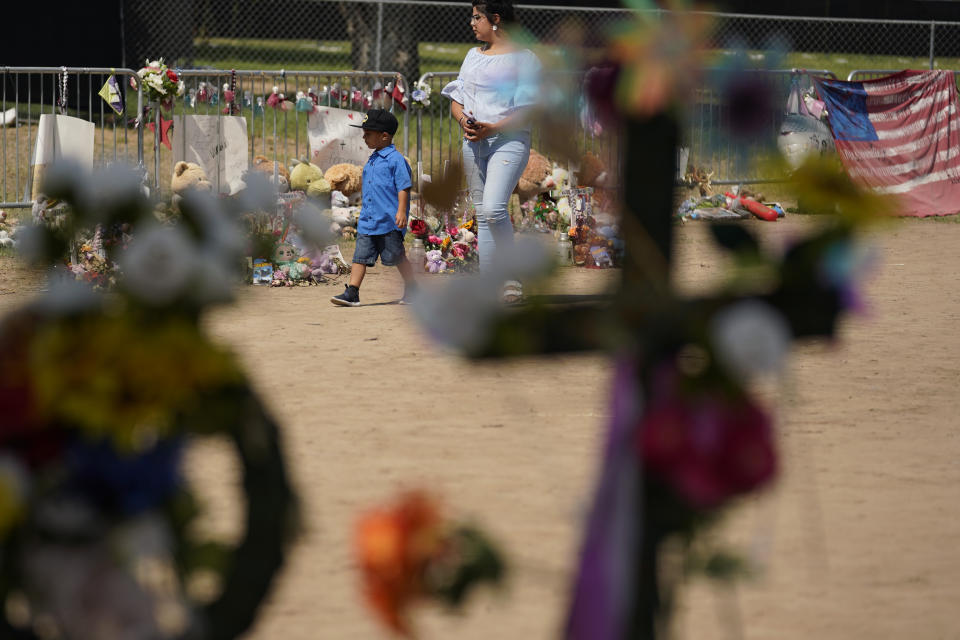 Visitors walk past a makeshift memorial honoring those recently killed at Robb Elementary School, Tuesday, July 12, 2022, in Uvalde, Texas. A Texas lawmaker says surveillance video from the school hallway where police waited as a gunman opened fire in a fourth-grade classroom will be shown this weekend to residents of Uvalde. (AP Photo/Eric Gay)