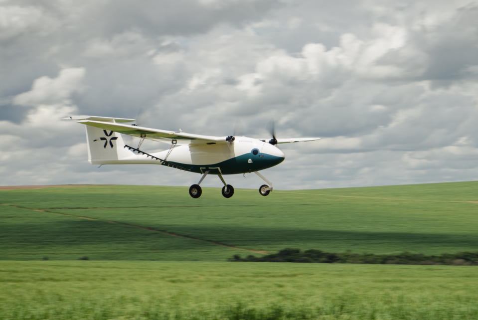 A Pyka Pelican aircraft flies close to a grassy field.