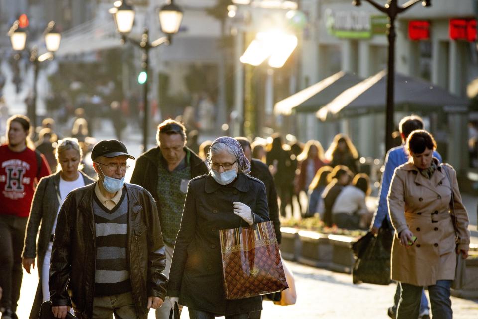 An elderly couple wearing face masks against coronavirus walk during a sunset in the center of in Moscow, Russia, Wednesday, Sept. 23, 2020. Russia confirmed over six and half thousand new Covid-19 cases Wednesday, bringing the country's official number of cases to 1,122,241 as the number of new infections across the country continues to rise. (AP Photo/Alexander Zemlianichenko)