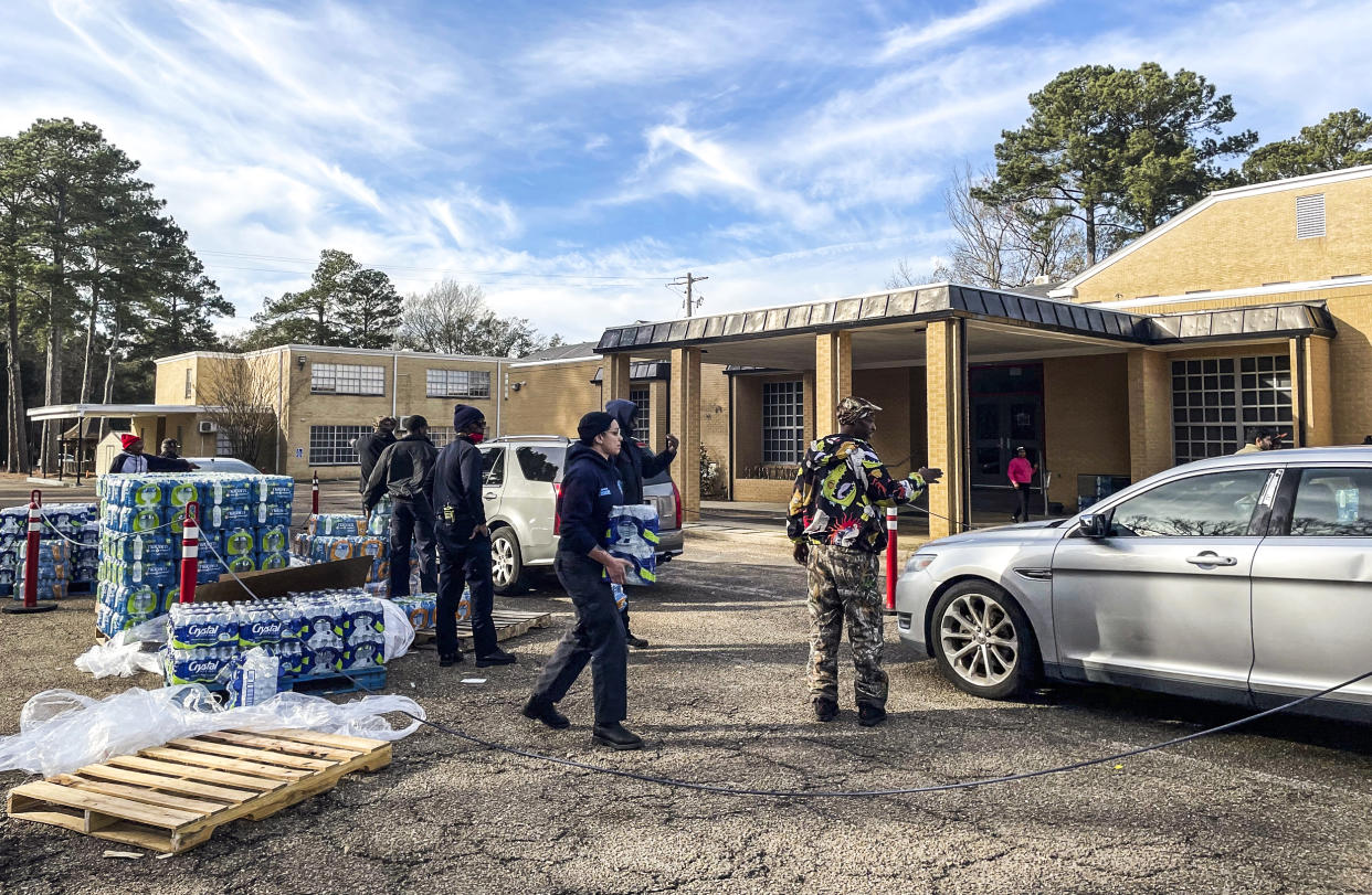 Image: A line of cars snakes past several city blocks as workers with the Mississippi Rapid Response coalition hand out bottled water to Jackson, Miss., residents on Dec. 27, 2022. (Michael Goldberg / AP file)