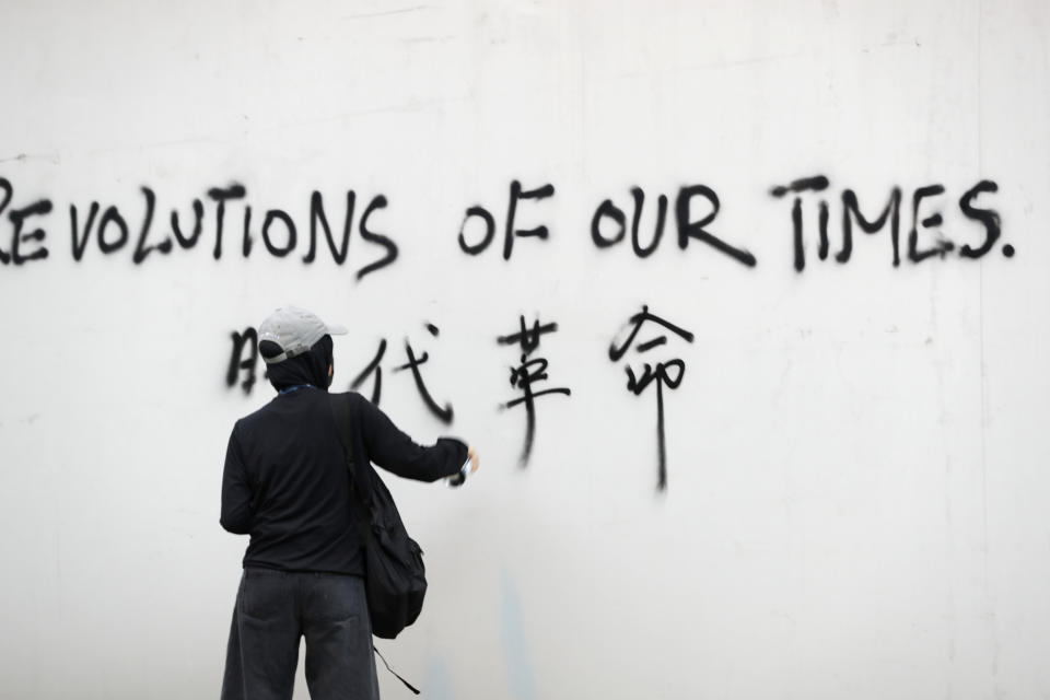 A protester spray-paints a slogan on a wall during a demonstration in Hong Kong, Saturday, Aug. 3, 2019. Hong Kong protesters ignored police warnings and streamed past the designated endpoint for a rally Saturday in the latest of a series of demonstrations targeting the government of the semi-autonomous Chinese territory. (AP Photo/Vincent Thian)