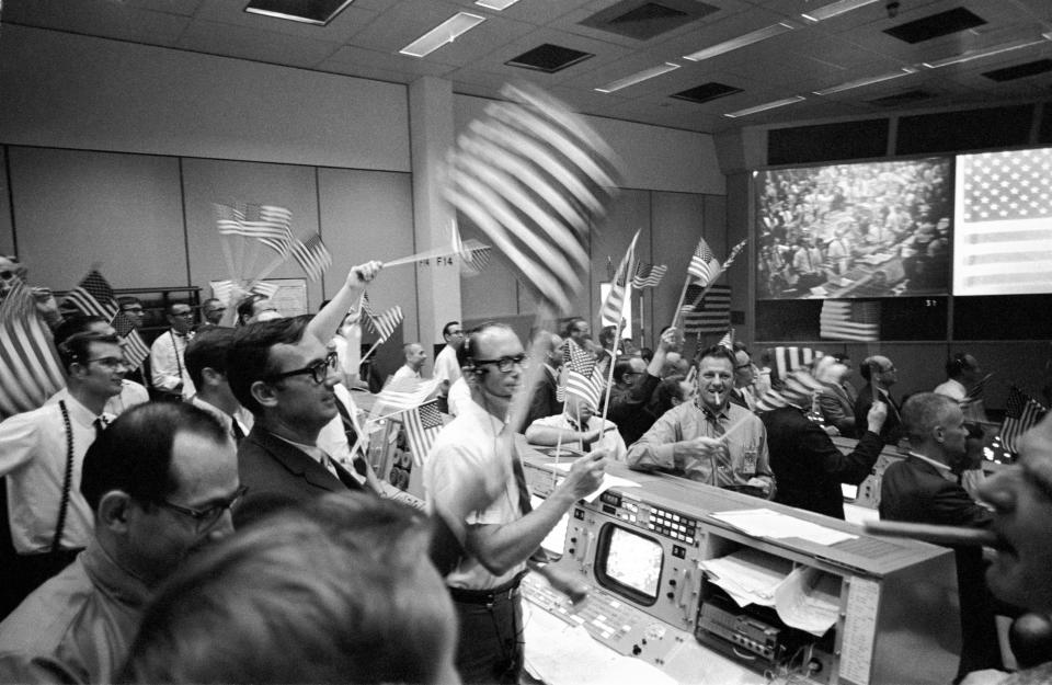 In this July 24, 1969 photo made available by NASA, flight controllers at the Mission Operations Control Room in the Mission Control Center at the Manned Spacecraft Center in Houston, celebrate the successful conclusion of the Apollo 11 lunar landing mission. (NASA via AP)