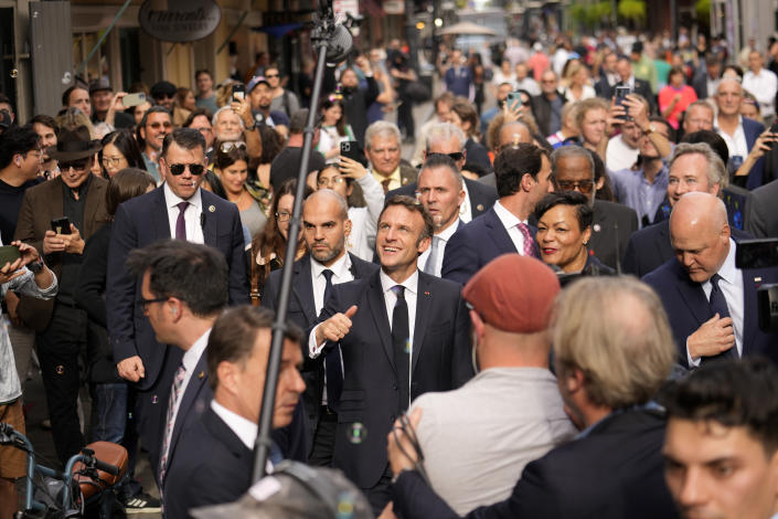 French President Emmanuel Macron reacts to crowds as he walks down Royal Street with New Orleans Mayor Latoya Cantrell and former Mayor Mitch Landrieu, right, in the French Quarter of New Orleans, Friday, Dec. 2, 2022. (AP Photo/Gerald Herbert)