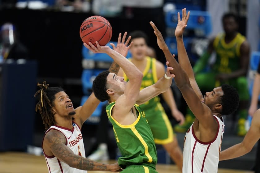 Oregon guard Chris Duarte, center, shoots between Southern California guard Isaiah White, left, and forward Evan Mobley, right, during the second half of a Sweet 16 game in the NCAA men's college basketball tournament at Bankers Life Fieldhouse, Sunday, March 28, 2021, in Indianapolis. (AP Photo/Jeff Roberson)